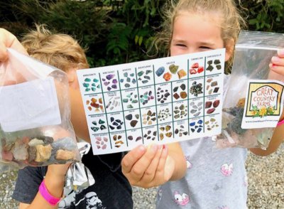 Proud young lady, "Gem Miners" hold up their ID card and bags of gems they discovered on their Great Country Farms Gem Tour Field Trip in Northern Virginia.