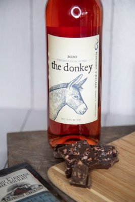 A bottle of Bluemont Vineyard's Farm Table Red Wine is displayed with Farmhouse Cocoa Nibs Alaskan Seasalt Chocolates in the Market at Great Country Farms