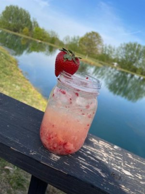 May mixology at Henway hard cider shows a Tequila Barrel aged cider mixed with fresh strawberries in a strawberry trimmed glass by the pond next to Great Country Farms.